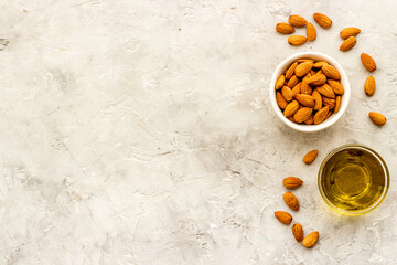 Sweet almond oil in glass jar and almond seeds with green leaf
