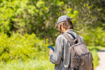 Male backpacker consults his mobile device to search for a route, travel concept.