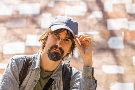 Man with long hair and blue cap looking at camera, travel concept.