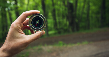 Compass in man hand in forest - obrazy, fototapety, plakaty