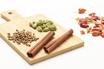 Cardamom and coriander seeds, cinnamon sticks on chalkboard.