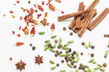 Cardamom seeds among allspice, star anise and dry red pepper pods on table.