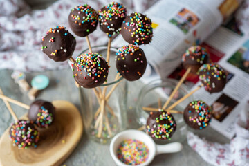 Delicious snack for children: chocolate cake pops in chocolate glaze on a stick in a glass. Close-up