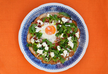 Homemade pizza with egg, spring onion, bacon, cheese and rucola. Top view of pizza