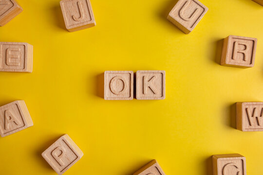 The word ok is made up of square wooden cubes with letters on a yellow background 