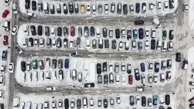 Bird's-eye view of a large number of cars of different brands and colors standing in a parking lot covered, with snow parking with cars top view with cars in winter with the effect of snow and