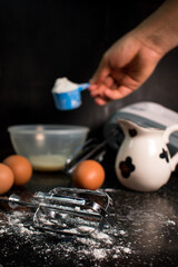 Milk, flour, eggs and blender stuff on a black table in the kitchen 