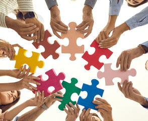 Teamwork. Pieces of colored puzzle in the arms of people standing in a circle and connecting them....