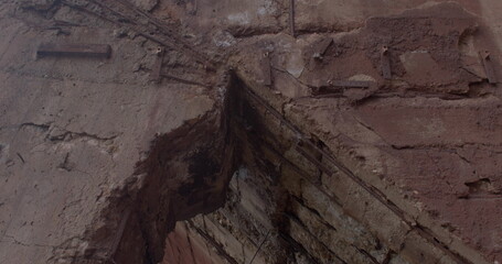 Concrete wall of an industrial building. Concrete damage at the corner. Massive columns support the weight of the structure. Yellow gas pipes.
