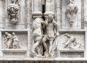 Marble sculpture depicting strong muscled telamons and other bas reliefs, detail on the façade of the Milan Cathedral, Lombardy region, Italy