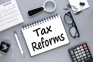 Tax reform . text on open notepad on gray background near white keyboard calculator