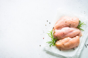 Chicken fillet with spices and herbs at whhite stone table. Top view with copy space.