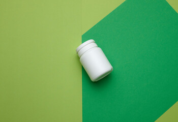 white plastic jar for pills, cream and medicines on a green background. Container for substances, top view