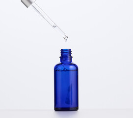 blue glass bottle with pipette for cosmetics, oils and serum. Advertising and product promotion