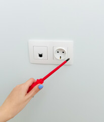 socket and connector for ftp cable installed in the wall. concept of repair, electrical. woman and repair, female hand installed socket. white socket on plain light wall