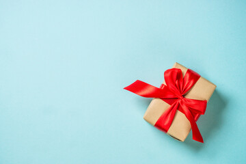 Christmas present box with red ribbon and glitter. Flat lay image on blue.