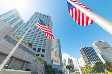 Skyscrapers and US flags in downtown Miami under a shining sun - obrazy, fototapety, plakaty