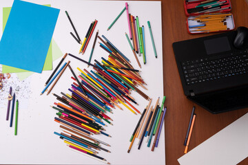drawing workstation with colored pencils paper and laptop