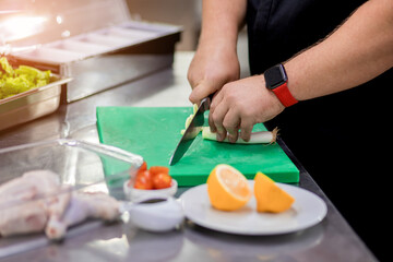 Obraz na płótnie Canvas The chef in the kitchen cuts freshly onions for preparing chicken dish