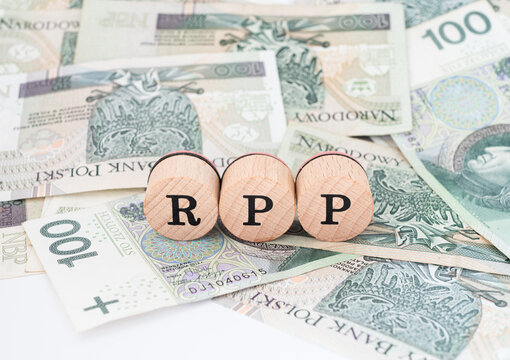 Word RPP written in polish with wooden blocks standing on money, "RPP" is a shortcut for The Monetary Policy Council