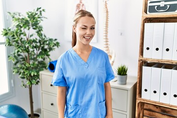 Young caucasian woman working at pain recovery clinic winking looking at the camera with sexy...