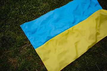The Ukrainian flag lies on the grass. background. War in Ukraine.