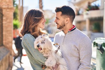 Man and woman holding dog standing together at street