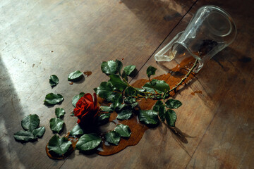 A fallen vase with a flower on the table. Love has passed.A rose in the water on the table.A broken heart.