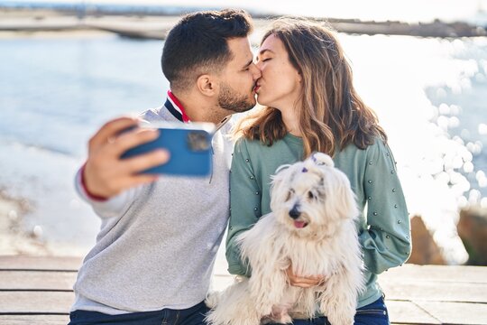 Man and woman holding dog making selfie by the smartphone at seaside