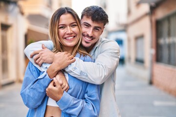 Fototapeta premium Young man and woman couple hugging each other standing at street
