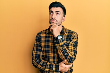 Young hispanic man wearing casual clothes with hand on chin thinking about question, pensive expression. smiling and thoughtful face. doubt concept.