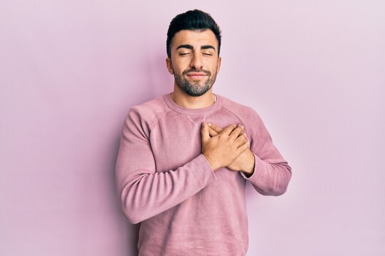 Young hispanic man wearing casual clothes smiling with hands on chest, eyes closed with grateful gesture on face. health concept.