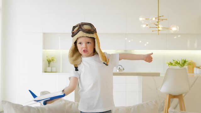 Cute 4 year old caucasian child in glasses and pilot hat plays at home with toy modern airplane, child dream of becoming pilot, thirst for travel, tourism and air travel. Kid play air craft toy home.