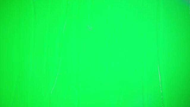 Rain on transparent glass close-up. Water drops falling down on green chroma key background. Wet window, autumn weather.