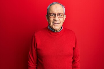 Handsome senior man with grey hair wearing casual clothes and glasses with a happy and cool smile...