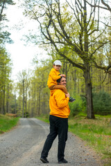 Obraz premium Father and son in yellow hoodies in forest in spring
