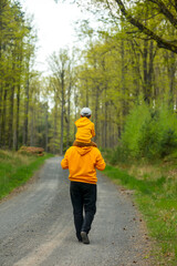 Father and son in yellow hoodies in forest in spring