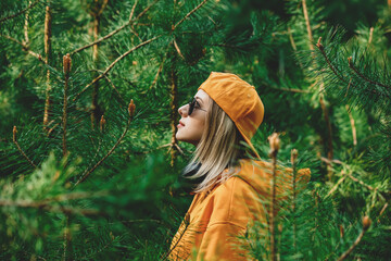 Stylish girl in hoodie listen music in headphones in pine tree forest