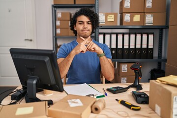 Hispanic man with curly hair working at small business ecommerce rejection expression crossing fingers doing negative sign