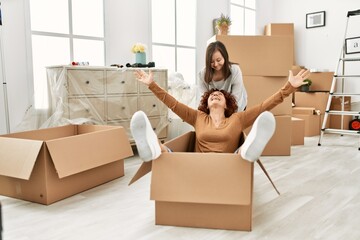 Mature mother and down syndrome daughter moving to a new home, having fun inside box