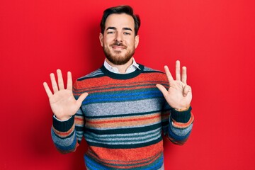 Naklejka premium Handsome caucasian man with beard wearing elegant wool winter sweater showing and pointing up with fingers number nine while smiling confident and happy.