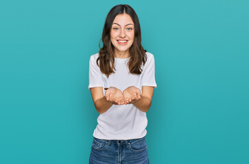 Young beautiful woman wearing casual white t shirt smiling with hands palms together receiving or giving gesture. hold and protection