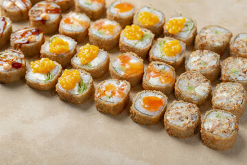 Set of different types of sushi and rolls on a light beige background