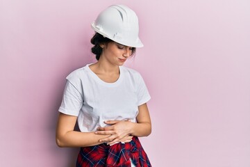 Young caucasian woman wearing hardhat with hand on stomach because indigestion, painful illness feeling unwell. ache concept.