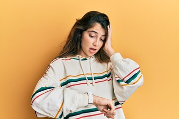 Young caucasian woman wearing casual clothes looking at the watch time worried, afraid of getting...
