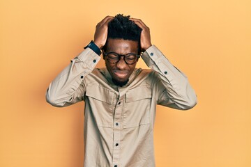 Young african american man wearing casual clothes and glasses suffering from headache desperate and...