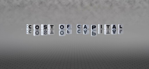 cost of capital word or concept represented by black and white letter cubes on a grey horizon background stretching to infinity