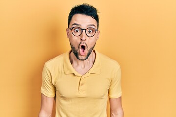 Young hispanic man wearing casual clothes and glasses afraid and shocked with surprise expression, fear and excited face.