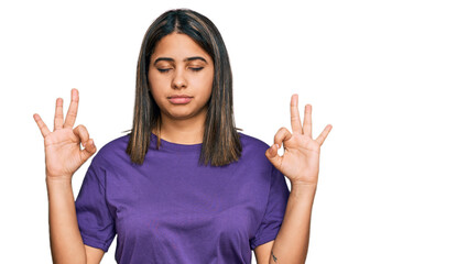 Young hispanic girl wearing casual purple t shirt relax and smiling with eyes closed doing meditation gesture with fingers. yoga concept.