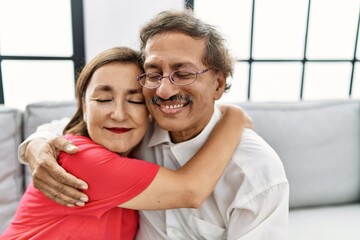 Middle age man and woman couple smiling confident hugging each other at home